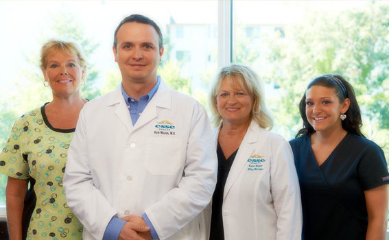 Esse Health medical team smiling in front of a window with greenery