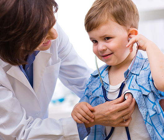 Doctor using a Stethoscope to check on a smiling young boy